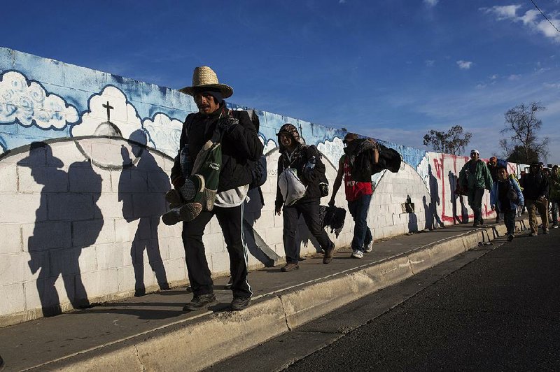 Members of the caravan of Central American migrants headed for the U.S. border leave Mexicali, Mexico, on Tuesday for the border city of Tijuana, where officials said they have arrested 34 migrants on minor offenses and turned them over for deportation. 