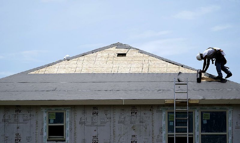 A construction worker puts down roofing paper in July on a new home near Houston, Texas. Home construction picked up in October on a rebound in multifamily housing, while single-family home starts fell for a second month. 