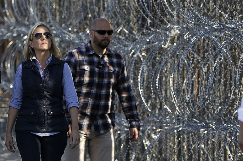 Homeland Security Secretary Kirstjen Nielsen inspects a section of razor-wire-fortified border wall between San Diego and Tijuana, Mexico, on Tuesday. Nielsen said a judge’s order blocking a new rule that denies protections to people who enter the country illegally was “dangerous.” 