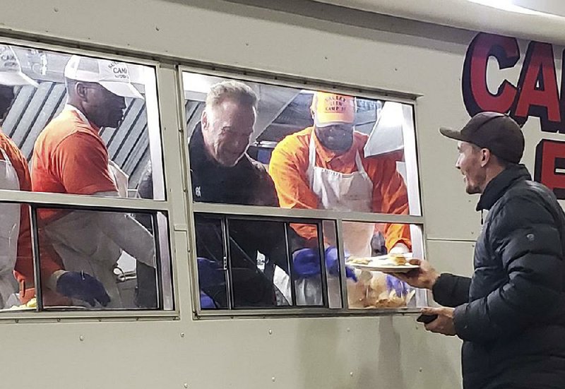 Former California Gov. Arnold Schwarzenegger (center) helps serve breakfast to firefighters Wednesday in Chico, Calif. “I wanted to let you know how much I appreciate all the work that you do,” he said in a brief speech during which he criticized President Donald Trump’s attack on forest management in the state. 