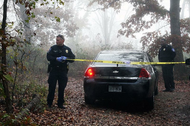 Hot Springs Police Cpl. Kenny May sections off part of a crime scene Wednesday in the 2200 block of Lakeshore Drive where police believe a Hot Springs woman killed her 8-year-old daughter and mother. 