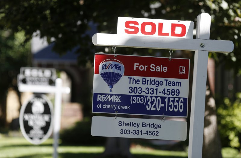 In this Aug. 30, 2018, file photo sold placards top sale signs outside homes on the market in Denver. On Wednesday, Nov. 21, the National Association of Realtors reports on sales of existing homes in October. (AP Photo/David Zalubowski, File)