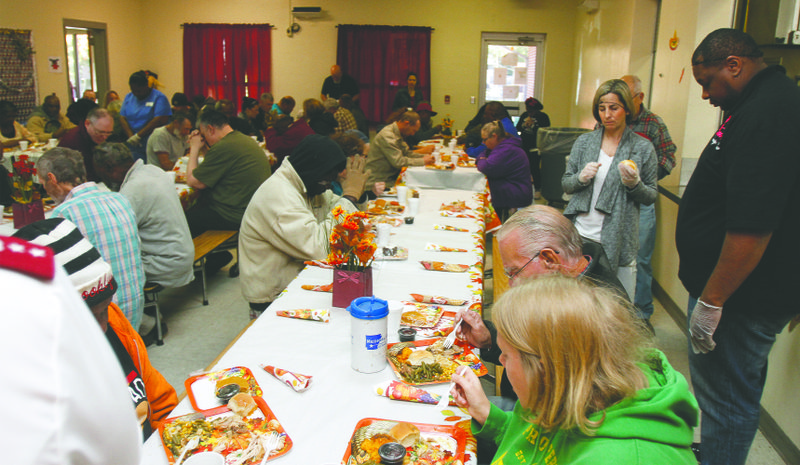 Grace: Guests and volunteers at the Salvation Army bow their heads in prayer as grace is said before Thanksgiving lunch on Thursday.