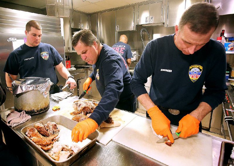 Little Rock firefighter Keith Lovell (right) and Capt. Jackie Rankin carve turkeys before Thanksgiving dinner Thursday at Fire Station 1.