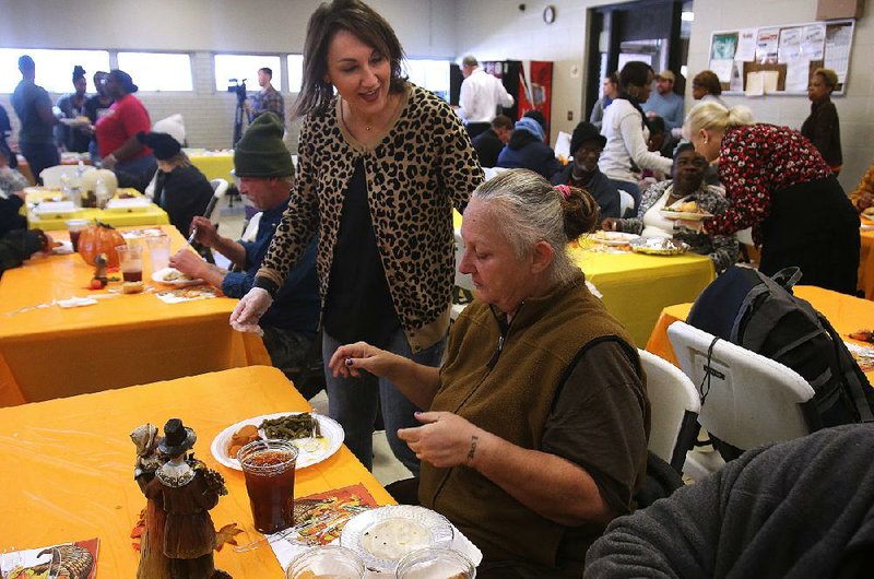Volunteer Gena McFadden (left) greets Debbie Oakley as she sits down for her Thanksgiving meal Thursday at the Salvation Army in Little Rock. 