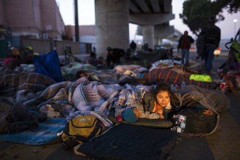 Early morning light illuminates the face of a migrant woman and her child as she wakes after sleeping under a bridge at the Chaparral border crossing in Tijuana, Mexico, Friday, Nov. 23, 2018. The mayor of Tijuana has declared a humanitarian crisis in his border city and says that he has asked the United Nations for aid to deal with the approximately 5,000 Central American migrants who have arrived in the city. (AP Photo/Rodrigo Abd)