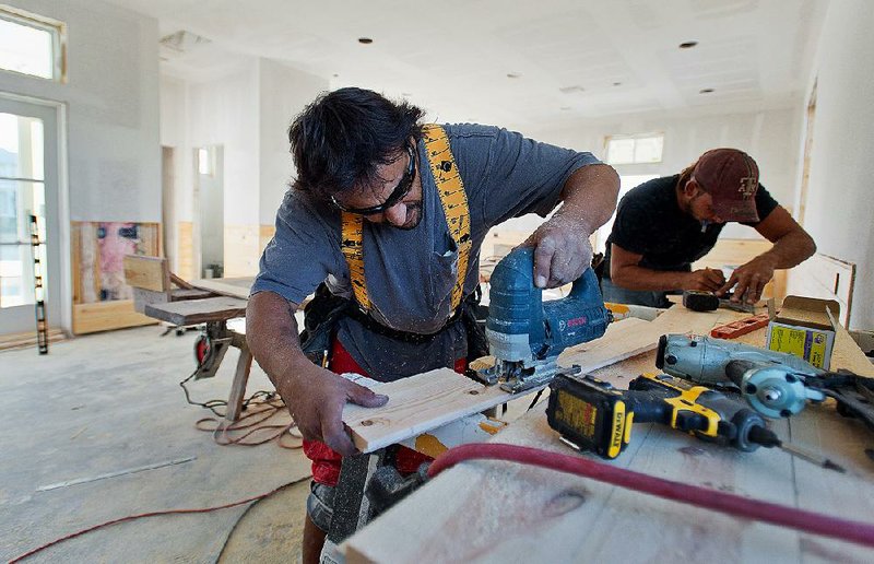 Carpenters trim pine siding for a new home at the Cinnamon Shore beachfront community in Port Aransas, Texas, in late 2012. 