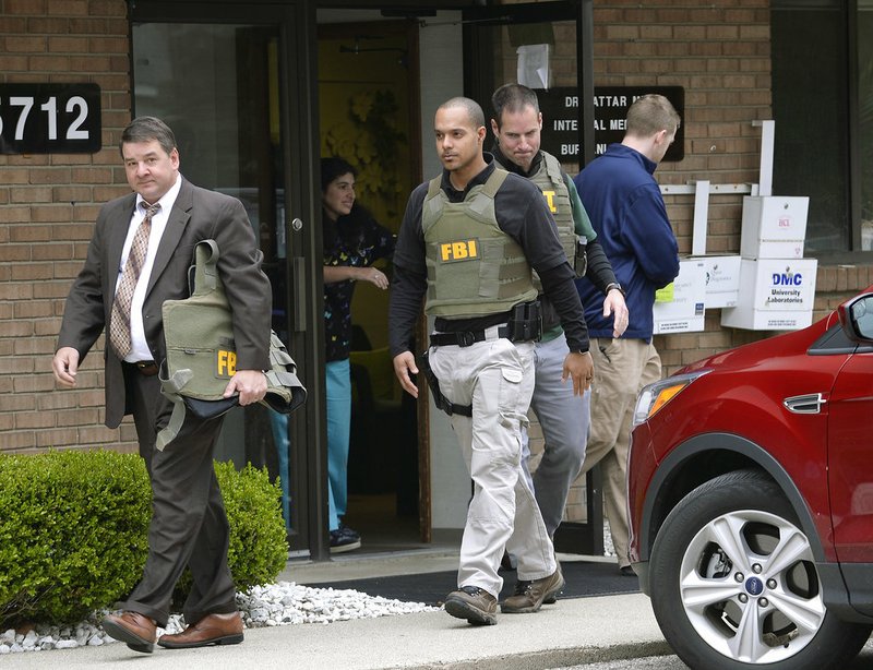 In this April 21, 2017 file photo, FBI agents leave the office of Dr. Fakhruddin Attar at the Burhani Clinic in Livonia, Mich., after completing a search for documents. A federal judge dismissed some charges Tuesday, Nov. 20, 2018, against eight people, including two doctors, in the genital mutilation of nine girls at the suburban Detroit clinic, finding it's up to states rather than Congress to regulate the practice. (Clarence Tabb Jr. /Detroit News via AP, File)