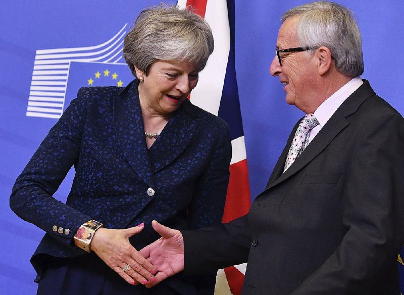 British Prime Minister Theresa May and European Commission President Jean-Claude Juncker share a greeting Saturday at the European Union headquarters in Brussels. 