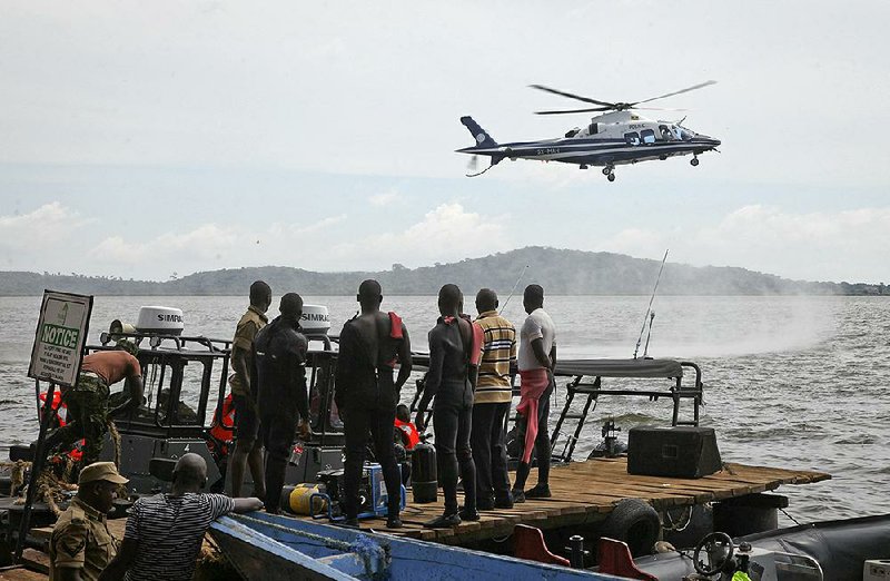 Ugandan divers look on as a helicopter searches for victims of a boat which capsized in Lake Victoria near the capital, Kampala, on Sunday. 