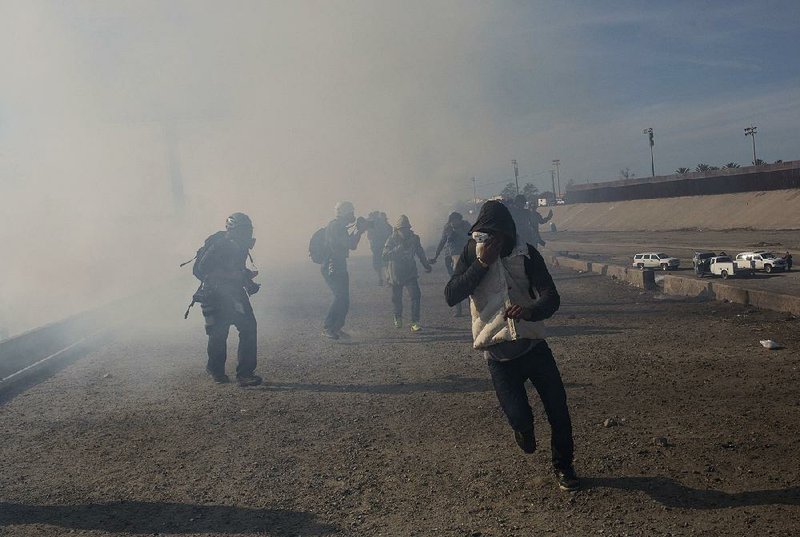 Central American migrants run from tear gas launched Sunday by U.S. agents after several migrants got past Mexican police at a border crossing in Tijuana, Mexico. 