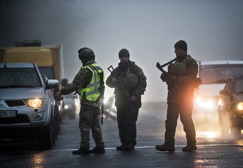 Ukrainian soldiers and police stop a car Tuesday at a checkpoint near the city of Mariupol, on the coast of the Sea of Azov. Coastal areas are subject to the martial-law declaration the Ukrainian government plans to impose today. 