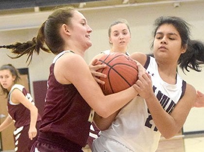 Lady Pioneer Ariel Nix and a Lady Wolf player fight for possession of a loose basketball during the Gentry-Lincoln basketball contest Nov. 19 in the gym a Lincoln High School. The battle for the ball occurred during the first round of the Lincoln Turkey Shoot Basketball Contest in Lincoln.