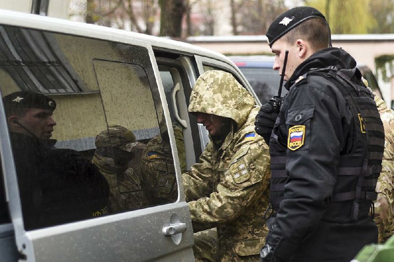 A Russian police officer escorts a Ukrainian sailor from court Wednesday in Simferopol, Crimea. The sailor was among 24 crew members arrested by Russians on three Ukrainian ships Sunday near the Kerch Strait. 