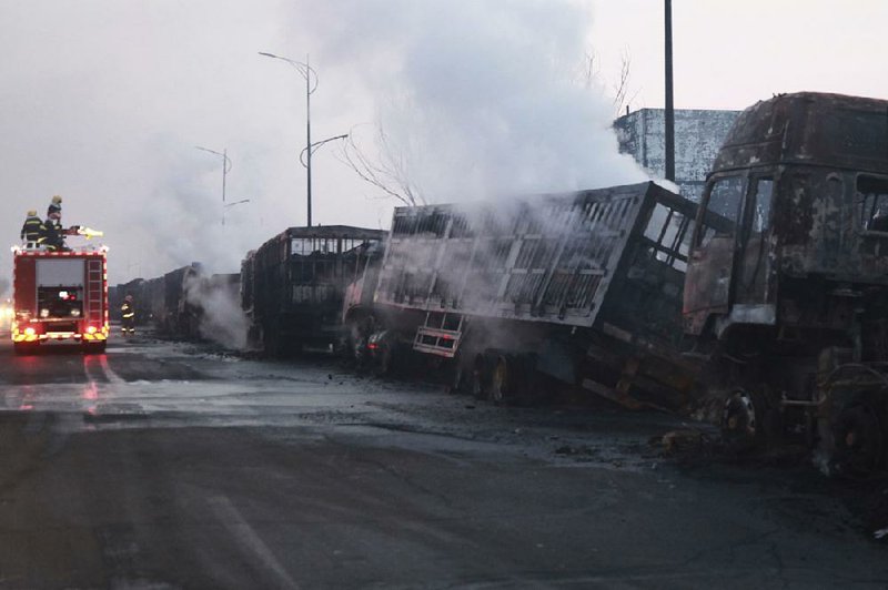 Firefighters work to extinguish some of the vehicles left in flames Wednesday after an explosion at a chemical plant in Zhangjiakou, China. 