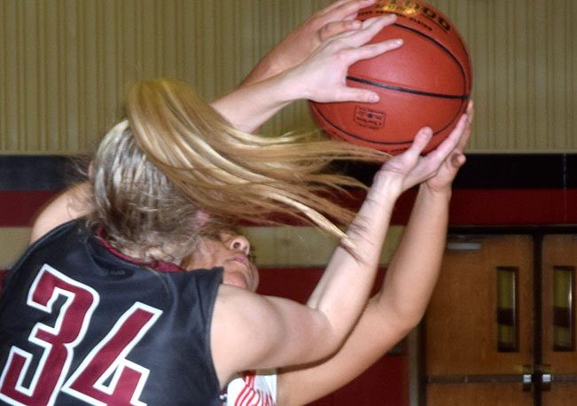 RICK PECK/SPECIAL TO MCDONALD COUNTY PRESS McDonald County's Rita Santillan takes a rebound away from Nevada's Payge Dahmer (34) during the Lady Mustangs' 53-28 loss on Nov. 26 in the C.J. Classic at Carl Junction High School.