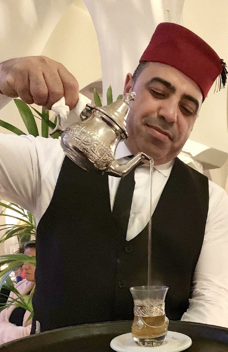 Rashid, a fez-topped waiter, pours sweet mint tea after dinner at Rick’s Cafe in Casablanca.