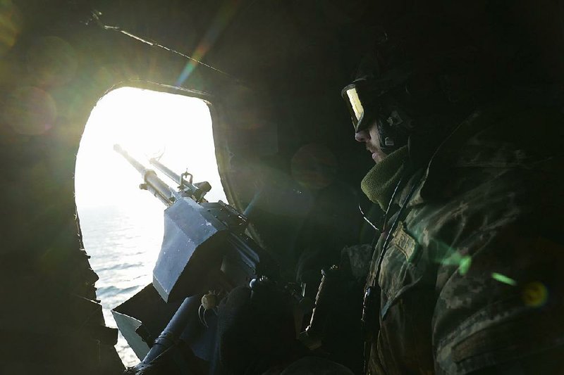 A Ukrainian soldier on a helicopter patrol Thursday scans the Sea of Azov near the Kerch Strait, where three Ukrainian vessels and more than 20 sailors were seized by Russia on Sunday. The sailors remain in Russian custody, and Ukraine is calling for NATO to deploy warships to the Sea of  Azov, which officials said is unlikely.