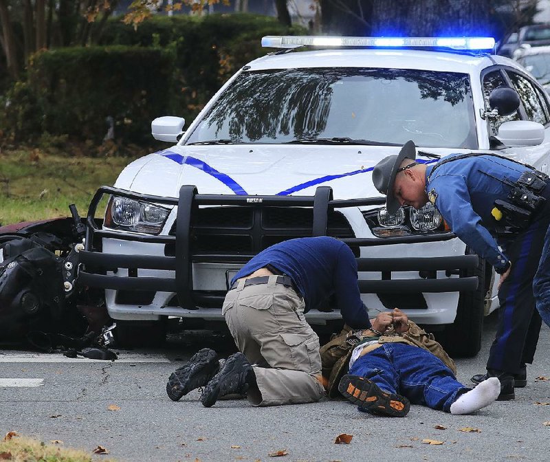 Law enforcement officers, including state troopers, check on a motorcyclist Thursday in North Little Rock after the rider crashed into a trooper’s vehicle while fleeing from state police.
