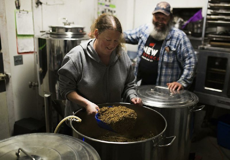 Liz Preston scoops mash grains for beer brewing as her husband Mark Preston watches at the Prestonrose Farm and Brewing Co. in Paris in November. 