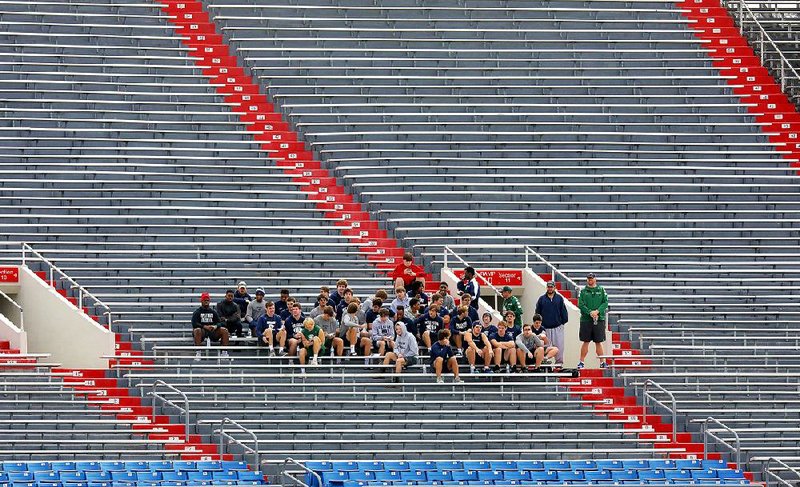 Members of the Little Rock Christian Academy football team watch and wait to practice at War Memorial Stadium in Little Rock Thursday morning. Little Rock Christian was scheduled to play Pulaski Academy tonight in the 5A championship game, but the game was moved to Sunday because of the threat of severe storms.

