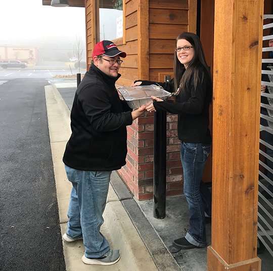 Submitted photo ON THE HOUSE: Ouachita Children’s Center Kitchen Manager Tyson Cooley, left, receives donated Texas Roadhouse meals from their marketing director, Amber Walsh, as part of the restaurant’s preparation before their grand opening Monday. The restaurant held a soft opening with donations collected to benefit OCC.