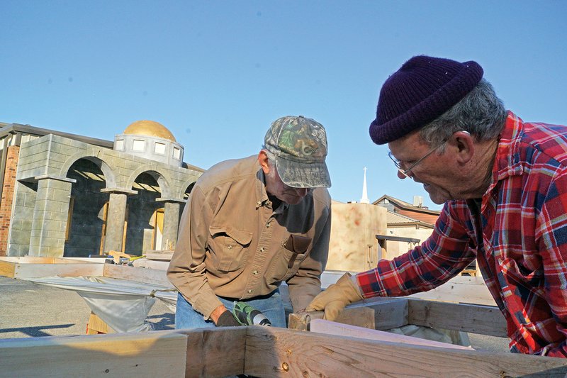 Gene Polk, left, works on the frame of one of the living-Nativity buildings that was damaged during high winds as Larry Barker pulls on the water-logged wood. The free 12th annual Searcy First Assembly of God Living Nativity started Nov. 30 and will continue from 5:30-8:30 p.m. today, 6:30-9:30 p.m.
Friday, 5:30-9:30 Saturday and 5:30-8:30 p.m. Dec. 9.