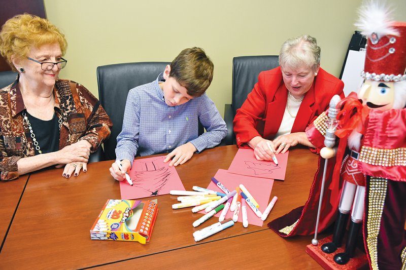 Mary Mosley, left, watches her 12-year-old grandson, Jackson Mosley, and Suzann Waggoner make holiday art similar to what may be created by those attending Saturday’s Nutcracker Sweets event. Mary Mosley and Waggoner are both members of the Conway Symphony Orchestra Guild, which sponsors the family event prior to the orchestra’s concert. Waggoner also made the red velvet cape for the nutcracker, “Sir Reginald,” which will be given away during the event.
