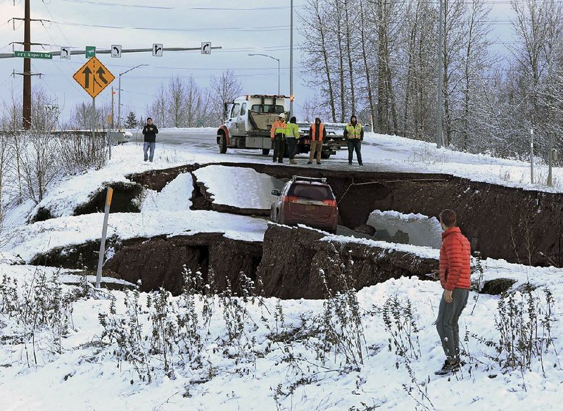 Highway workers respond to a car stuck in a section of an off-ramp in Anchorage, Alaska, that collapsed Friday morning when a magnitude 7.0 earthquake struck. It caused extensive damage, but no deaths or serious injuries were reported.