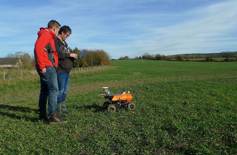 Joe Allnutt (left) and Thomas Burrell with British startup Small Robot Co. operate a farming robot named Tom during a trial Friday in East Meon, England. 