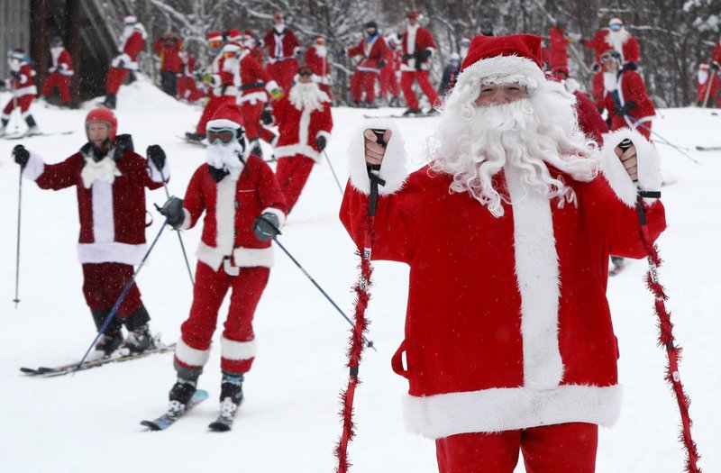 Skiers and snowboarders dressed as Santa Claus head downhill during the annual Santa Sunday event Dec. 2, 2018, in Newry, Maine. The red-suited lookalikes aim to put a smile on people’s faces while raising money for charity. (AP Photo/Robert F. Bukaty)