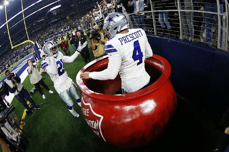 Dallas Cowboys quarterback Dak Prescott celebrates after being lifted into a Salvation Army kettle by running back Ezekiel Elliott following his touchdown against the Washington Redskins on Nov. 22 in Arlington, Texas. Elliott was fined $13,369 on Saturday for placing both money and Prescott in the kettle.