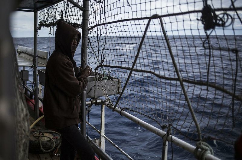A migrant looks out to sea Saturday from the Spanish fishing vessel Nuestra Madre de Loreto carrying migrants rescued off the coast of Libya. 