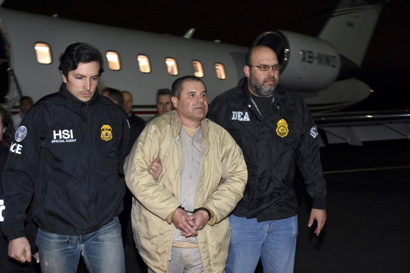FILE - In this Jan. 19, 2017, file photo, provided by U.S. law enforcement, authorities escort Joaquin &quot;El Chapo&quot; Guzman, center, from a plane to a waiting caravan of SUVs at Long Island MacArthur Airport, in Ronkonkoma, N.Y. On Monday, Nov. 26, 2018, a government witness testifying at the U.S. trial of the Mexican drug lord known as &quot;El Chapo&quot; claims his cartel paid massive bribes to a top law enforcement official. (U.S. Law Enforcement via AP, File)