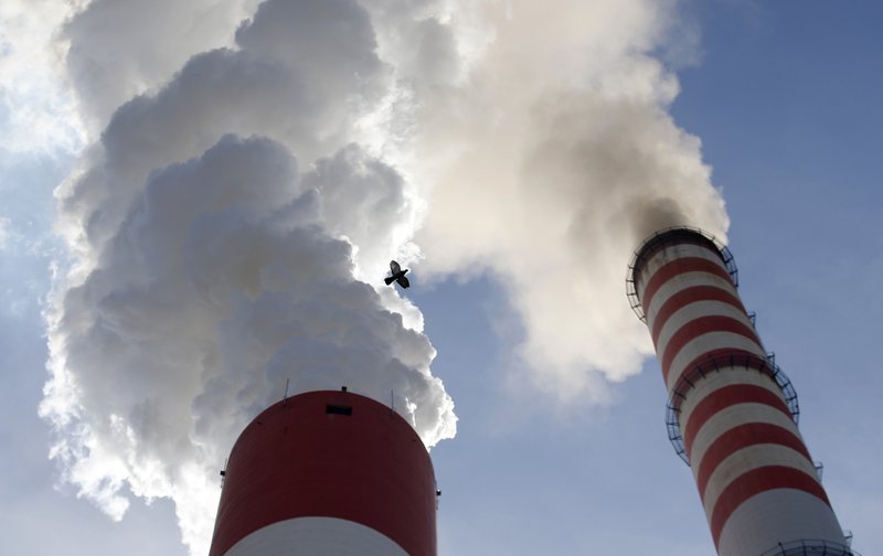 In this photo taken Wednesday, Oct. 3, 2018, a bird flies past as smoke emits from the chimneys of Serbia's main coal-fired power station near Kostolac, Serbia. The COP 24 UN Climate Change Conference is taking place in Katowice, Poland. Negotiators from around the world are meeting for talks on curbing climate change. (AP Photo/Darko Vojinovic)