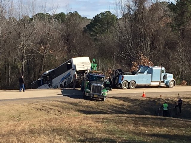 Crews work to remove a bus from an area of the highway where it crashed early Monday.