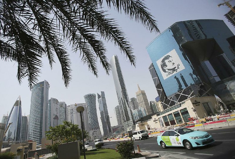 A taxi passes a building with an image of the emir of Qatar, Sheikh Tamim bin Hamad Al Thani, in Doha, Qatar in May. The tiny Persian Gulf state announced Monday that it will withdraw from OPEC in January. 
