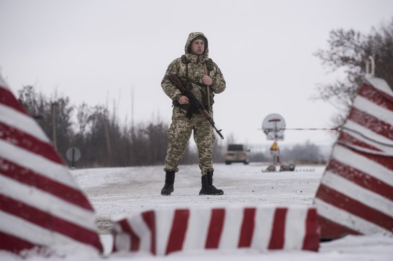 A Ukrainian border guard stands ready at the border from Russia to Ukrainian side of the Ukraine - Russia border in Milove town, eastern Ukraine, Sunday, Dec. 2, 2018. On a map, Chertkovo and Milove are one village, crossed by Friendship of Peoples Street which got its name under the Soviet Union and on the streets in both places, people speak a mix of Russian and Ukrainian without turning choice of language into a political statement. (AP Photo/Evgeniy Maloletka)