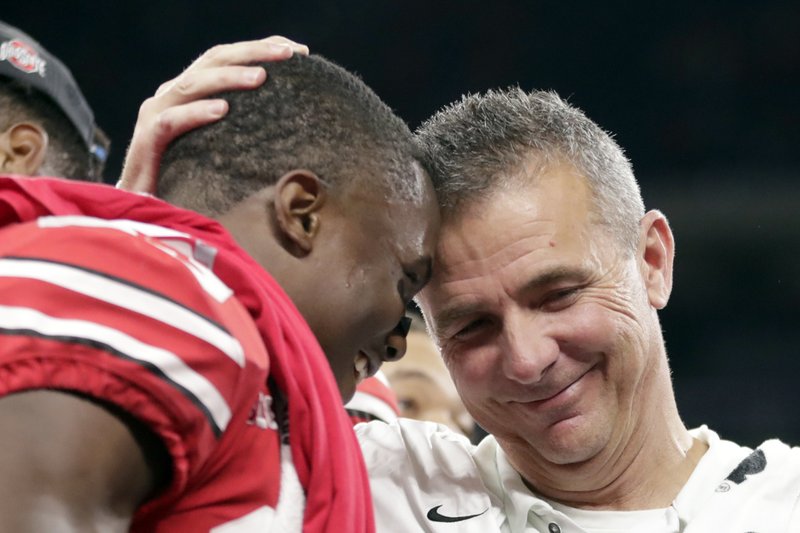 FILE - In this Dec. 2, 2018, file photo, Ohio State head coach Urban Meyer and wide receiver Terry McLaurin, left, celebrate early after defeating Northwestern 45-24 in the Big Ten championship NCAA college football game in Indianapolis. Meyer, the highly successful coach who won three national championships and sparked controversy and criticism this season for his handling of domestic violence allegations against a now-fired assistant, will retire after the Rose Bowl, the university announced Tuesday, Dec. 4, 2018.(AP Photo/Michael Conroy, File)

