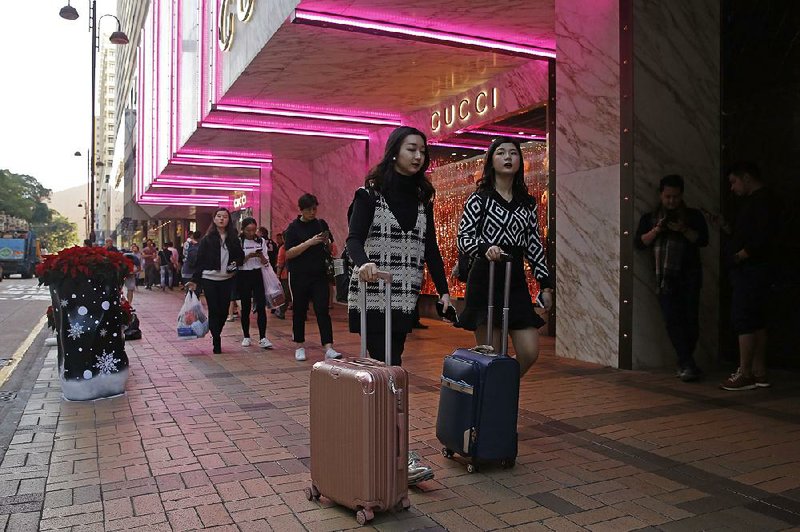 Chinese tourists walk on the Canton Road, the one-stop-shopping street of high-end brands in Hong Kong, in late November. Chinese purchases of luxury goods from designer boutiques of Manhattan and Paris are down this year amid cooling economic growth in China. 