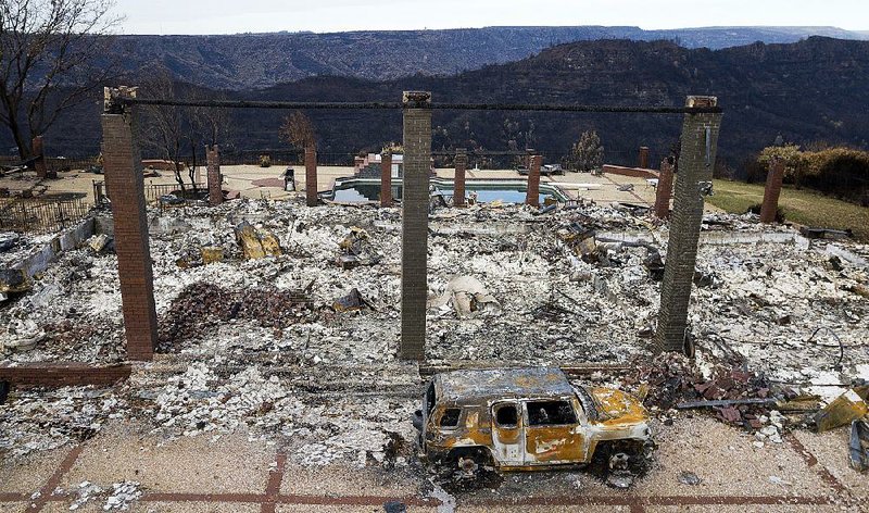 A burned vehicle sits Monday among the ashes in Paradise, Calif. Last month’s wildfire in the Paradise area destroyed nearly 14,000 homes and killed at least 85 people. 