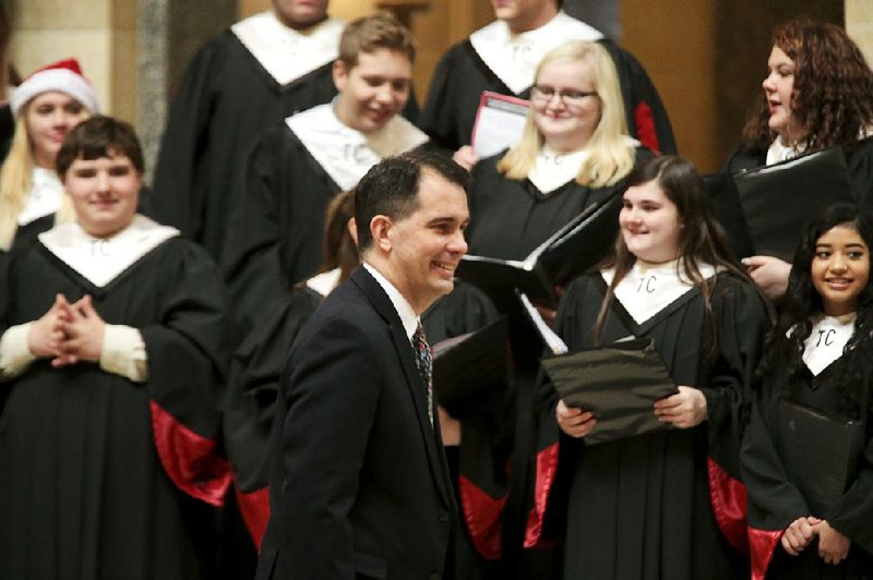 Wisconsin Gov. Scott Walker arrives Tuesday for the lighting of the Christmas tree in the state Capitol rotunda in Madison. Protesters drowned out a high school choir on hand for the ceremony.  