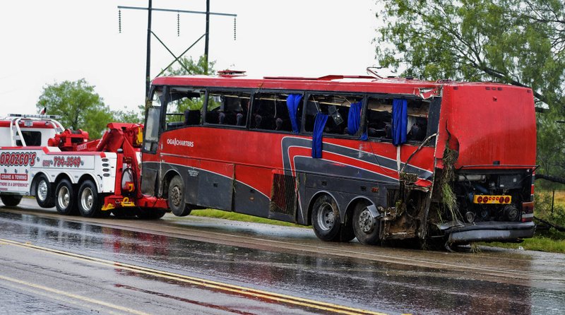 FILE - In this May 14, 2016, file photo, a damaged charter bus is hauled away after a fatal rollover in far South Texas. The National Transportation Safety Board released its final report on the crash Tuesday, Dec. 4, 2018, saying the Texas driver suffering from &quot;acute sleep deficit&quot; failed to maintain his lane and caused his passenger bus to careen out of control, causing a wreck. (Danny Zaragoza/The Laredo Morning Times via AP, File)