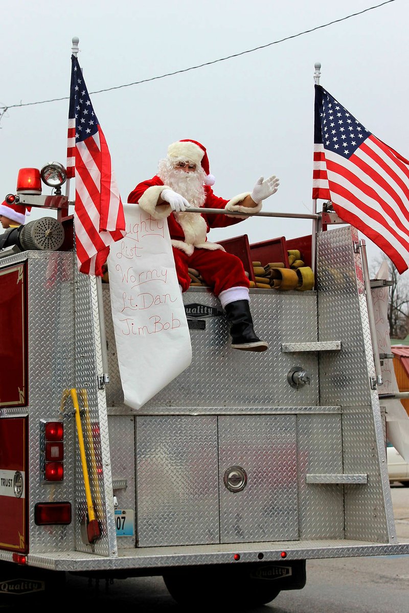 MEGAN DAVIS MCDONALD COUNTY PRESS/Saint Nick was spotted on the back of Southwest City's fire engine. The Naughty List next to him reads: Wormy, Lt. Dan, and JimBob (McGhee).