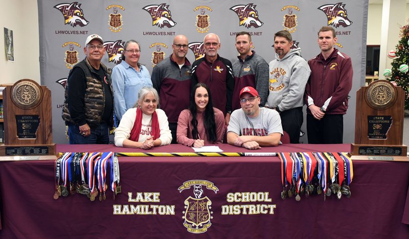 The Sentinel-Record/Grace Brown HOG SIGNING: Lake Hamilton senior Edie Murray, center, signs a letter of intent with the University of Arkansas' track and field program Wednesday at Lake Hamilton High School. Murray is accompanied in front by her mother, Darbi Murray, left, and father, Todd Murray; and back, from left, grandparents, Sue and Billy Murray; and coaches Morry Sanders, Karl Koonce, Brandon Starr, Lewis Hunt and Brandon Smith.