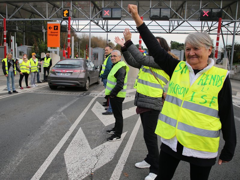 A demonstrator wearing a yellow jacket reading &quot; Macron give us the wealth tax&quot; protests at the toll gates on a motorway at Biarritz southwestern France, Wednesday, Dec.5, 2018.The concessions made by French president Emmanuel Macron's government in a bid to stop the huge and violent anti-government demonstrations seemed on Wednesday to have failed to convince protesters, with trade unions and disgruntled farmers now threatening to join the fray.(AP Photo/Bob Edme)