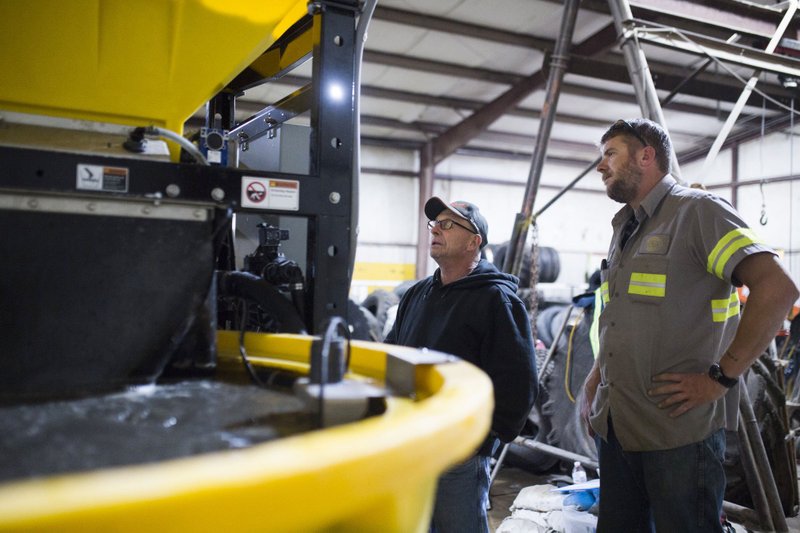 NWA Democrat-Gazette/CHARLIE KAIJO Steve Trogdon (left), road superintendent, and Patrick Clanton examine a brine maker at Benton County's Road Department in Bentonville. The brine maker mixes salt and water, the mixture used to treat the roads in Benton County.