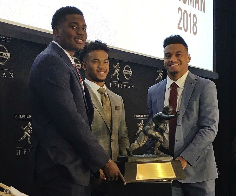 Heisman Trophy finalists (from left) Dwayne Haskins (Ohio State), Kyler Murray (Oklahoma) and Tua Tagovailoa (Alabama) pose with the Heisman Trophy at the New York Stock Exchange on Friday in New York. A quarterback will win college football’s most coveted individual award for the 16th time in the past 19 years.