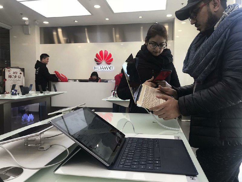 Tourists examine a laptop computer Thursday at a Huawei store in Beijing. Meng Wanzhou, Huawei Technologies’ chief financial officer, was arrested in Canada last weekend on fraud charges and faces extradition to the U.S.