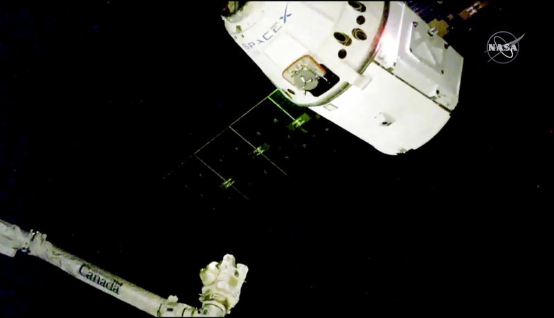 In this image taken from NASA Television, the SpaceX Dragon cargo spacecraft approaches the robotic arm for docking to the International Space Station, Saturday, Dec. 8, 2018. SpaceX delivery full of Christmas goodies has arrived at the International Space Station. The Dragon capsule pulled up at the orbiting lab Saturday, three days after launching from Cape Canaveral, Florida. It took two tries to get the Dragon close enough to be captured by the space station's robot arm. The hour-and-a-half delay was caused by trouble with the communication network that serves the space station.(NASA TV via AP)